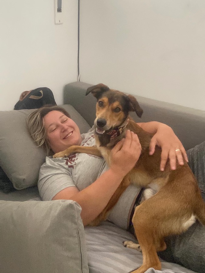 Halyna cuddling a happy dog at home on the sofa