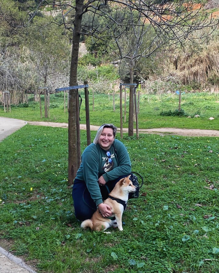 Halyna smiling with a dog in a park in Cascais